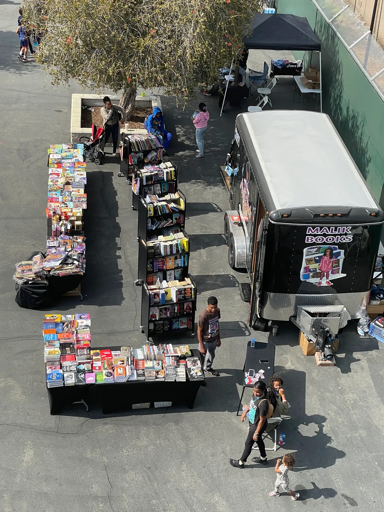Outdoor Malik Books book fair with tables of books and the Malik's Bookmobile van Outdoor Malik Books book fair with tables of books and the Malik's Bookmobile van