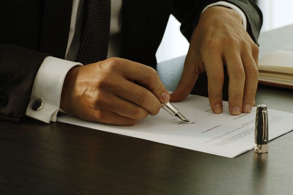 A close-up of a person signing a document

AI-generated content may be incorrect.