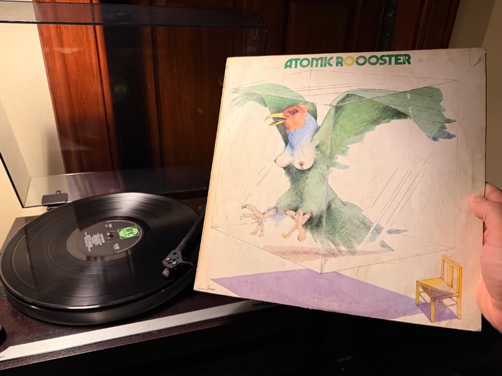 My hand holding up the Atomic Rooster LP with a picture of a bird with its boobs out. It's not a rooster.