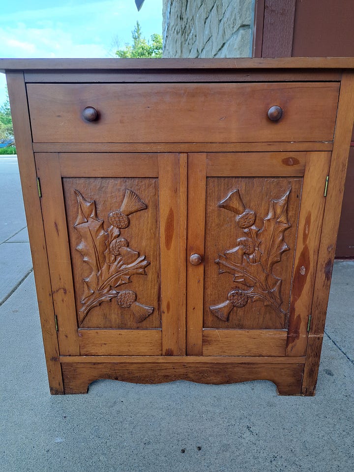 Wood cabinet with thistle carvings on doors