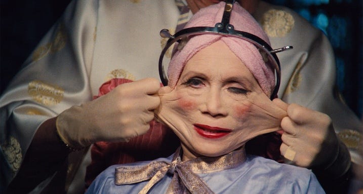 Cosmetic surgery still — Katherine Helmond undergoes grotesque facial stretching in a satirical plastic surgery scene from Brazil (1985).