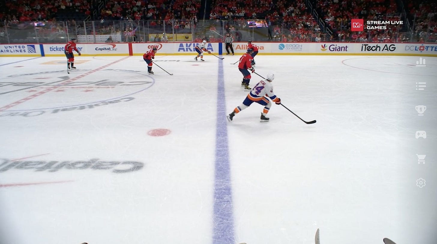 An image showing the side angle of a hockey rink. You can see that the Islanders are off-sides and there should be no goal.