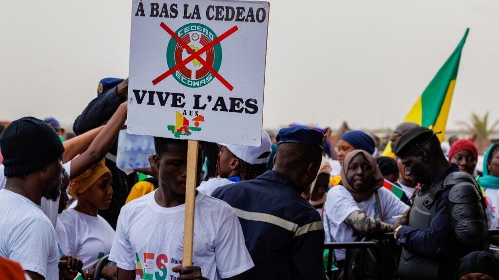 A supporter of the Alliance of Sahel States holds a placard reading "Down with Ecowas, long live the ASS" during a rally to celebrate Mali, Burkina Faso and Niger leaving the bloc in Bamako, Mali, in February 2024. 
