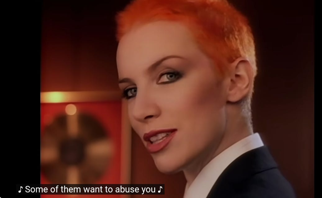 A frame from the "Sweet Dreams" music video by Eurythmics. A subtitle reads "Some of them want to abuse you," a lyric from the song.