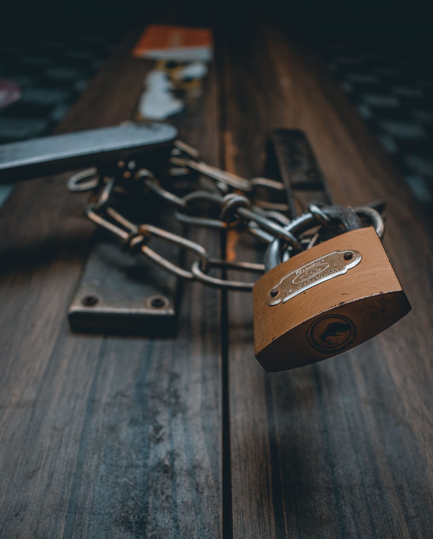 a brown padlock on a chain around a door handle a brown padlock on a chain around a door handle