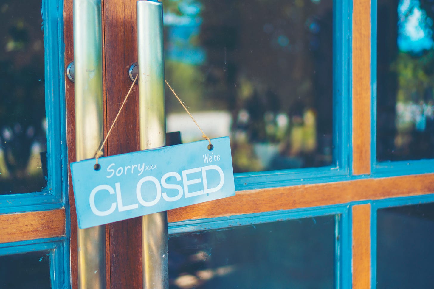Sign hanging on store door reading "Sorry, we're closed"