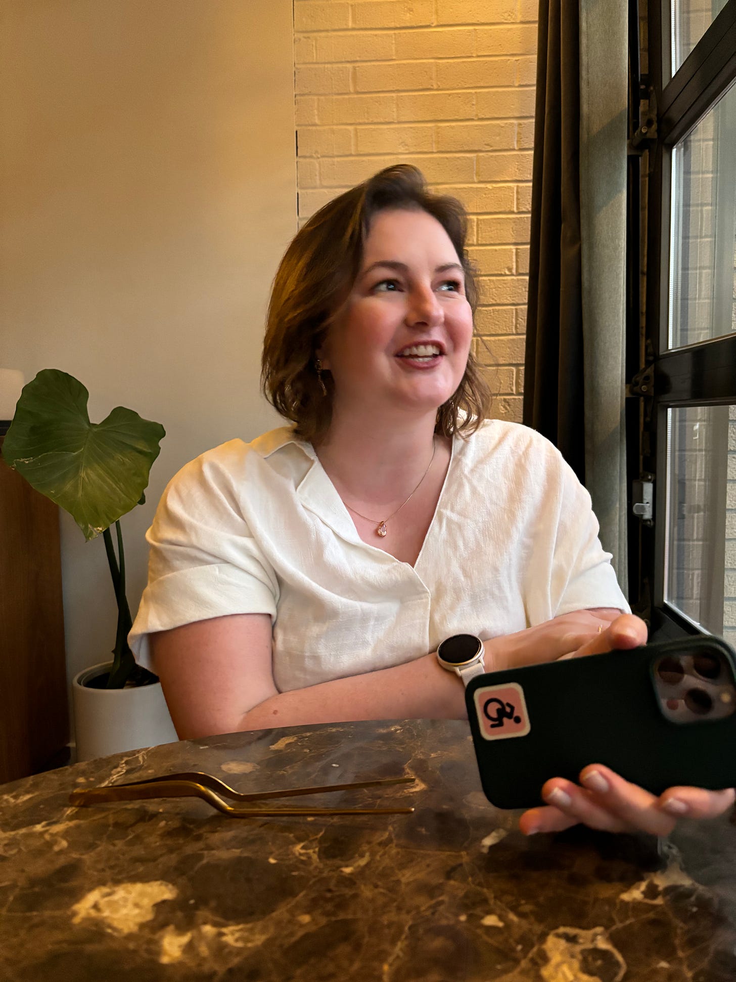 A white woman with short brown hair is seated and looking out a window