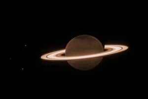 Image of Saturn and some of its moons, captured by the James Webb Space Telescope’s NIRCam instrument on June 25, 2023. In this monochrome image, NIRCam filter F323N (3.23 microns) was color mapped with an orange hue.