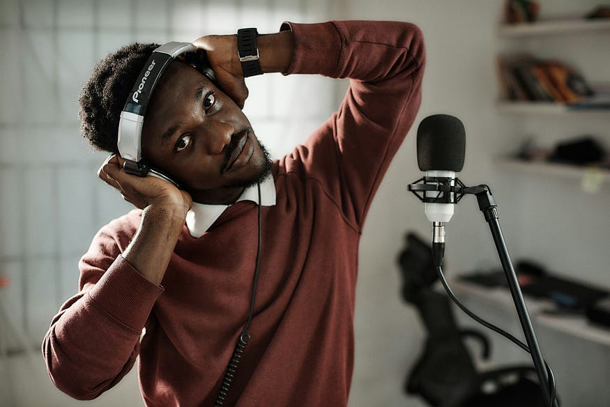 a man with headphones on, standing in front of a microphone. a man with headphones on, standing in front of a microphone.