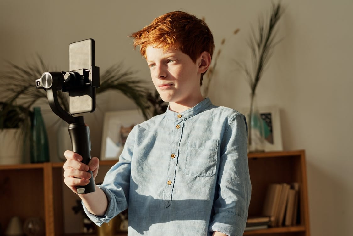 Free Boy in Blue Dress Shirt Holding Black Selfie Stick Stock Photo