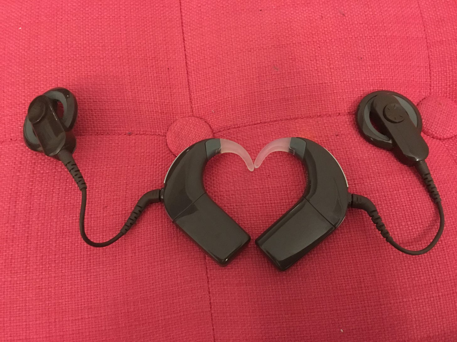 Mes deux implants cochléaires de couleur marron sont côte à côte et forment un coeur. En arrière plan, la couleur rose. Mes deux implants cochléaires de couleur marron sont côte à côte et forment un coeur. En arrière plan, la couleur rose.