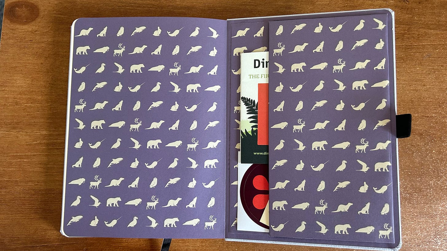 The expandable wallet inside the back cover of a Dingbats Earth Collection Notebook. The paper is covered with many cream coloured artic animals on a purple background.