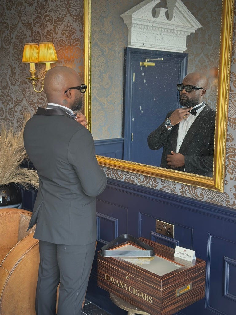 Kurtis Pykes adjusting the bow tie of his suit in the mirror
