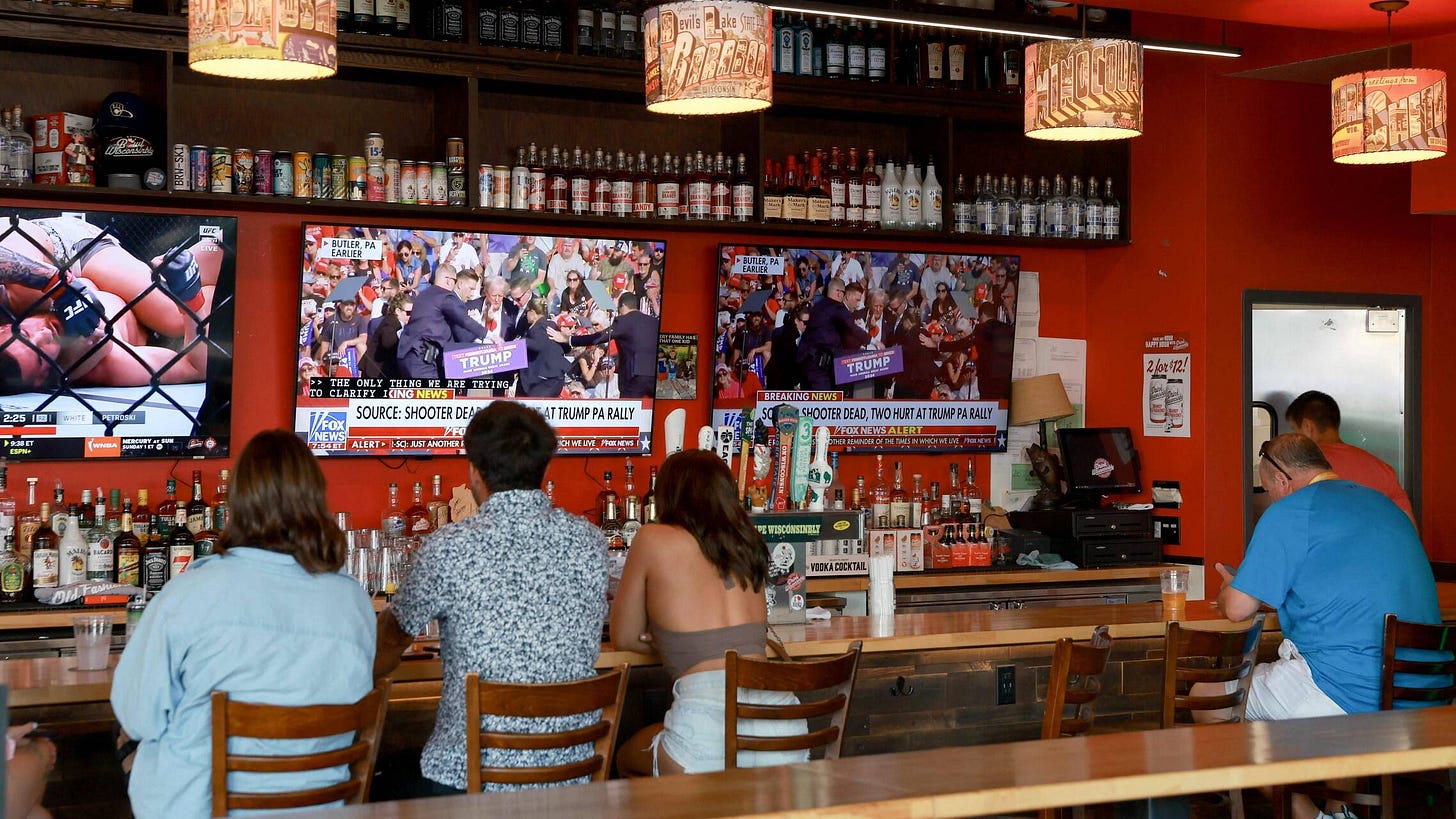 Des personnes regardent une retransmission du meeting de Donald Trump lors duquel il a été blessé. Dans un bar situé en face du Fiserv Forum où s'est tenue la Convention nationale républicaine, le 13 juillet 2024, à Milwaukee, dans le Wisconsin. — © JOE RAEDLE / Getty Images via AFP Des personnes regardent une retransmission du meeting de Donald Trump lors duquel il a été blessé. Dans un bar situé en face du Fiserv Forum où s'est tenue la Convention nationale républicaine, le 13 juillet 2024, à Milwaukee, dans le Wisconsin. — © JOE RAEDLE / Getty Images via AFP