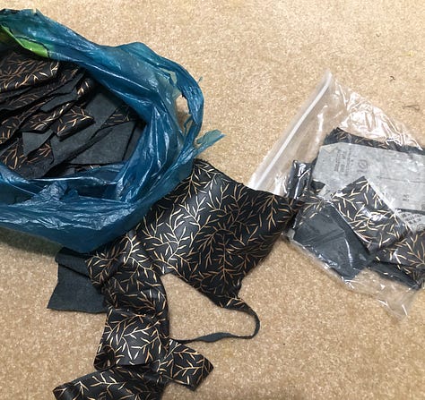 Gallery of sparkly costumes and costuming supplies, two wigs in golden brown on mannequin heads, and gold-leaf leather in a pile on the floor.