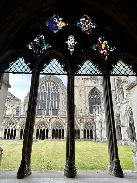 White woman poses awkwardly in front of cathedral and gardens