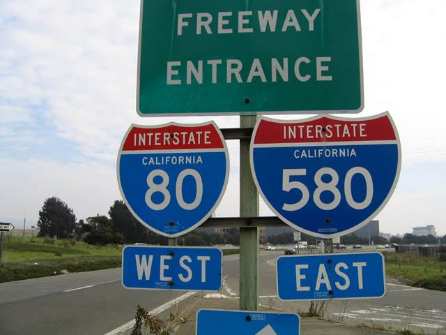 Photo of 3 freeway signs on a roadway. They read "Interstate California 80 West" and Internet California 580 East."