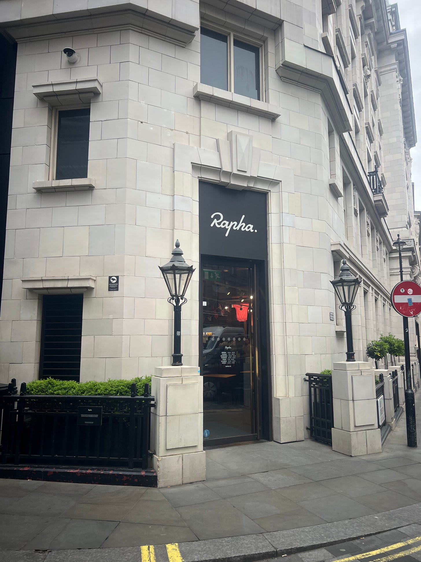 The exterior of Rapha’s London Clubhouse, a discreet entrance on a white stone building with the Rapha logo on a dark fascia. The exterior of Rapha’s London Clubhouse, a discreet entrance on a white stone building with the Rapha logo on a dark fascia.