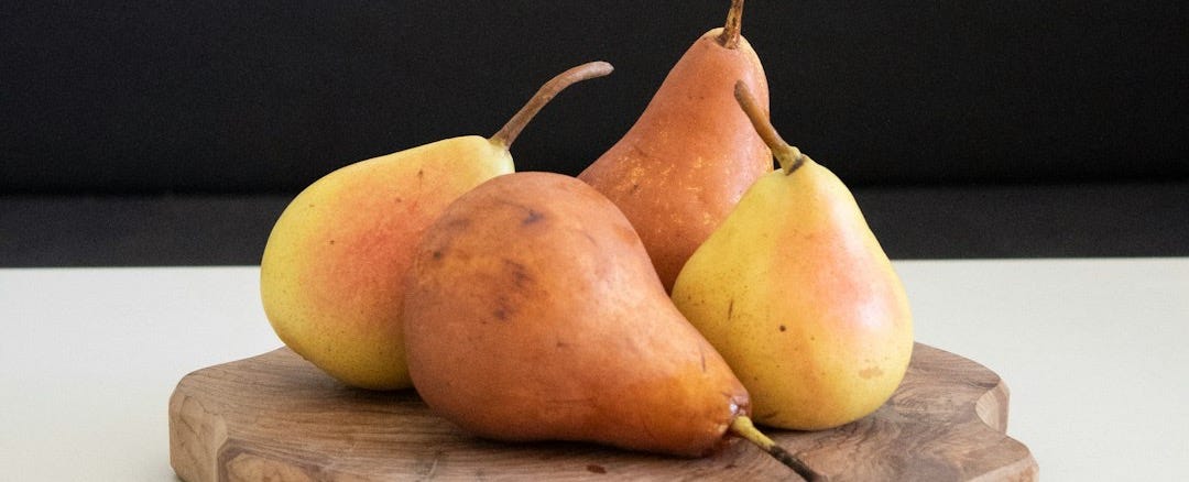 four orange pears fruits on brown wooden board panel