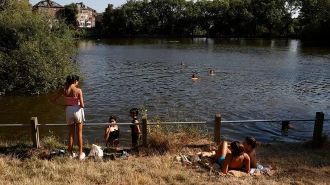 People have a swim on a pond in Hampstead Heath park to cool off from the heat.
