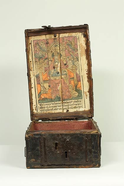 The inside of the lid of the Bodleian Book Coffer and its rare woodcut print depicting “God the Father in Majesty.” Under the vividly colored depiction of god is a prayer, in Latin, which would have been chanted on special feast days. (Bodleian Libraries / University of Oxford)