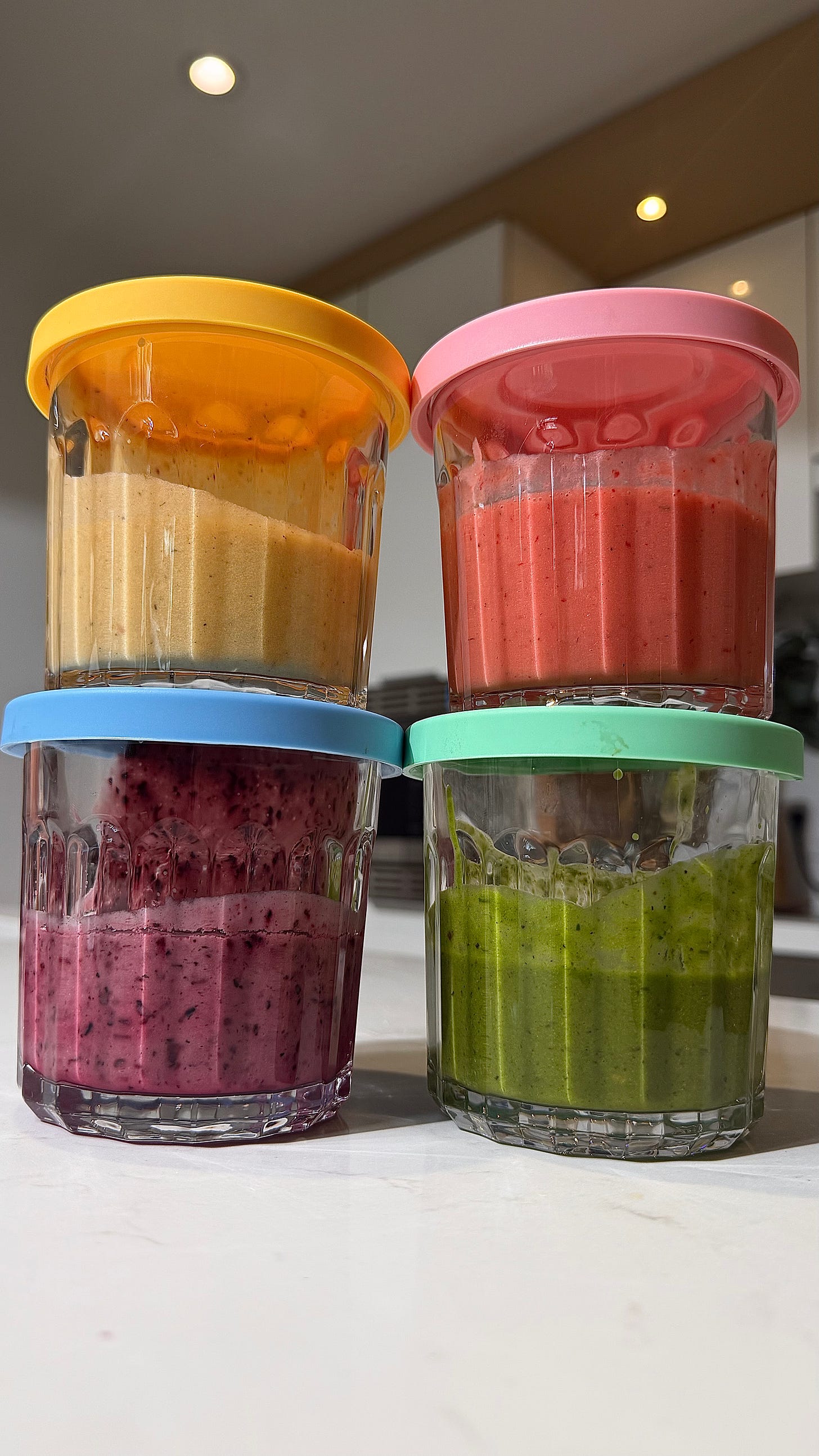 Four homemade summer fruit salad dressings in glass jars with colorful lids — peach brown butter, strawberry balsamic, blueberry basil, and chimichurri