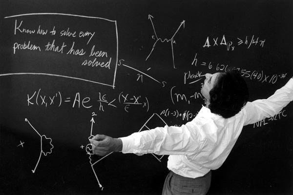 This may contain: a man writing on a blackboard with white chalk and some type of formula written on it