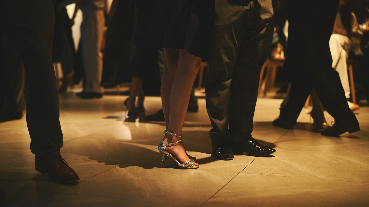 A dance floor with couples shown from the waist down. We see beautiful shoes paired with each other.