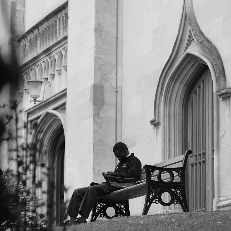 a person sitting on a bench in front of a building a person sitting on a bench in front of a building
