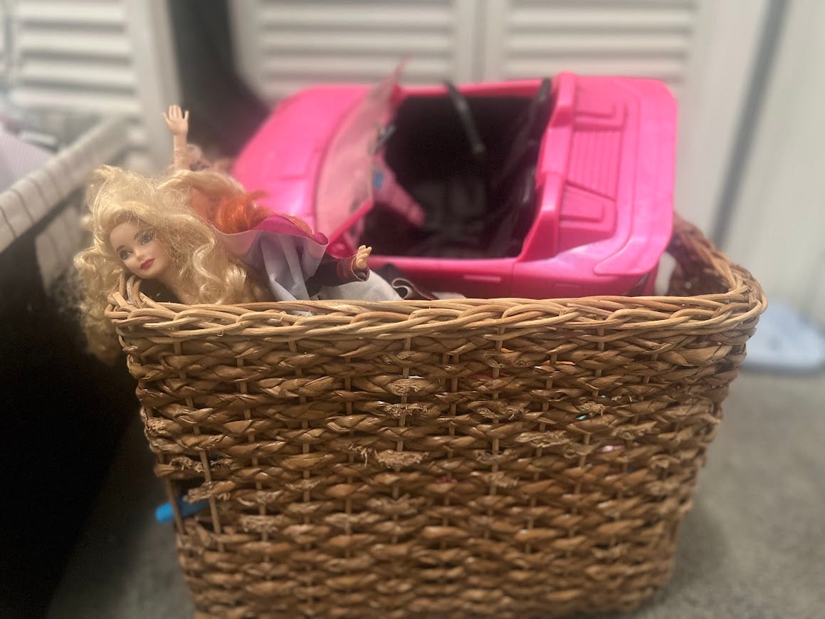 A wicker basket full of Barbie stuff.