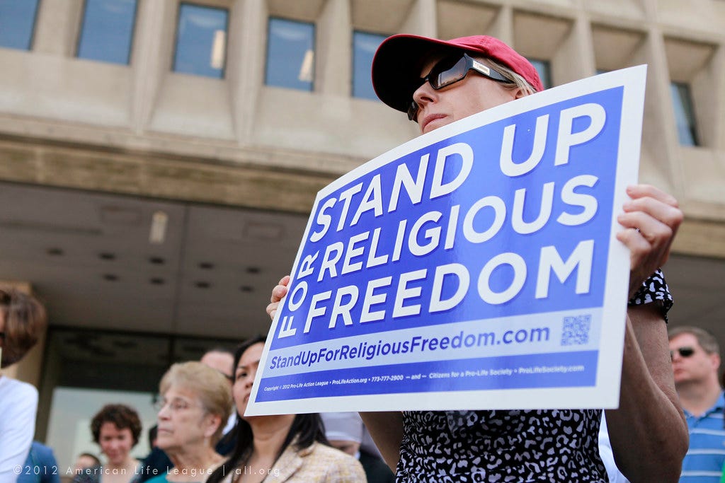 Demonstrator holding sign that reads "Stand Up for Religious Freedom" Demonstrator holding sign that reads "Stand Up for Religious Freedom"