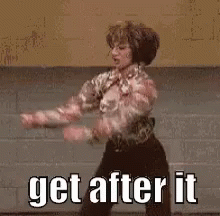 a woman is dancing on a stage with the words `` get after it '' behind her .