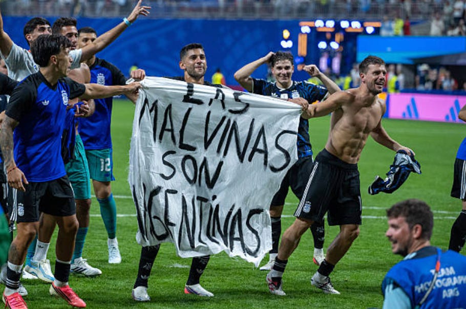 ATLANTA, GEORGIA - JULY 15: Lisandro Martinez, Cristian Romero, Giovani Lo Celso with a banner during the FIFA World Cup 2026 Semi Final match between England and Argentina at Atlanta Stadium on July 15, 2026 in Atlanta, Georgia. The banner refers to the British Overseas Territory of the Falkland Islands, located off the coast of Argentina. Argentina disputes British sovereignty over the islands and refers to them as Las Malvinas. (Photo by Sebastian Frej/Getty Images)