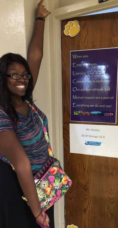 A tall Black woman (Dr. J) standing outside of a classroom door