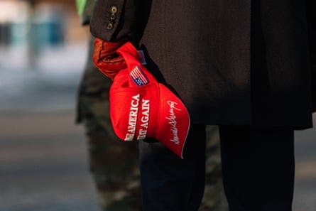 Hand at person’s side holds red cap