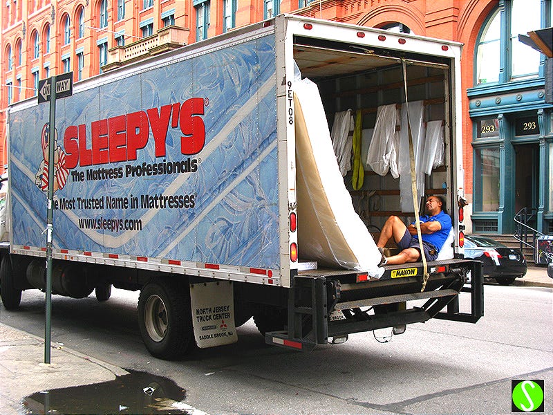 photo of delivery man napping in 'SLEEPY'S' mattress delivery truck