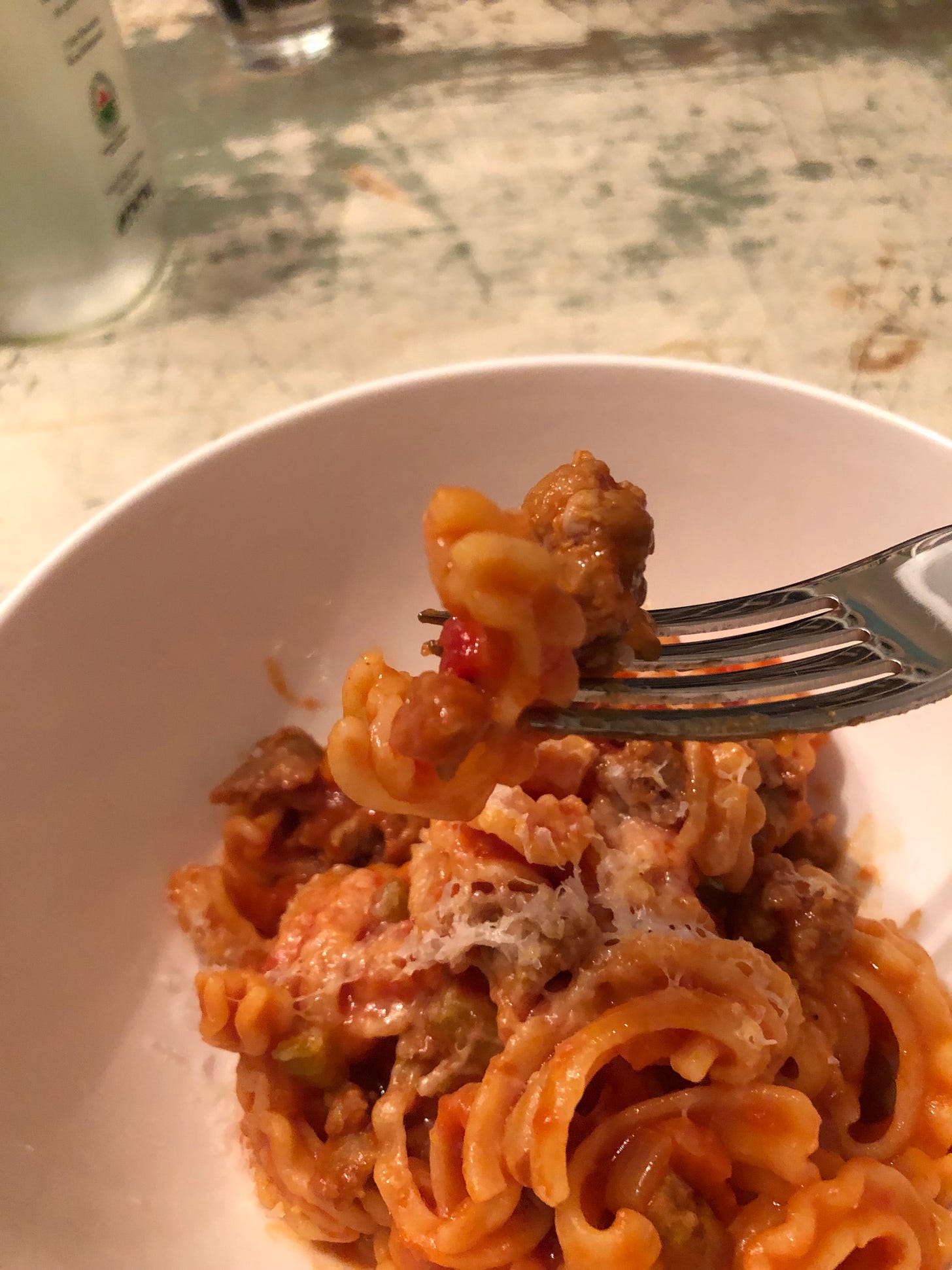 A cascatelli noodle coated in tomato sauce is speared on a fork. 