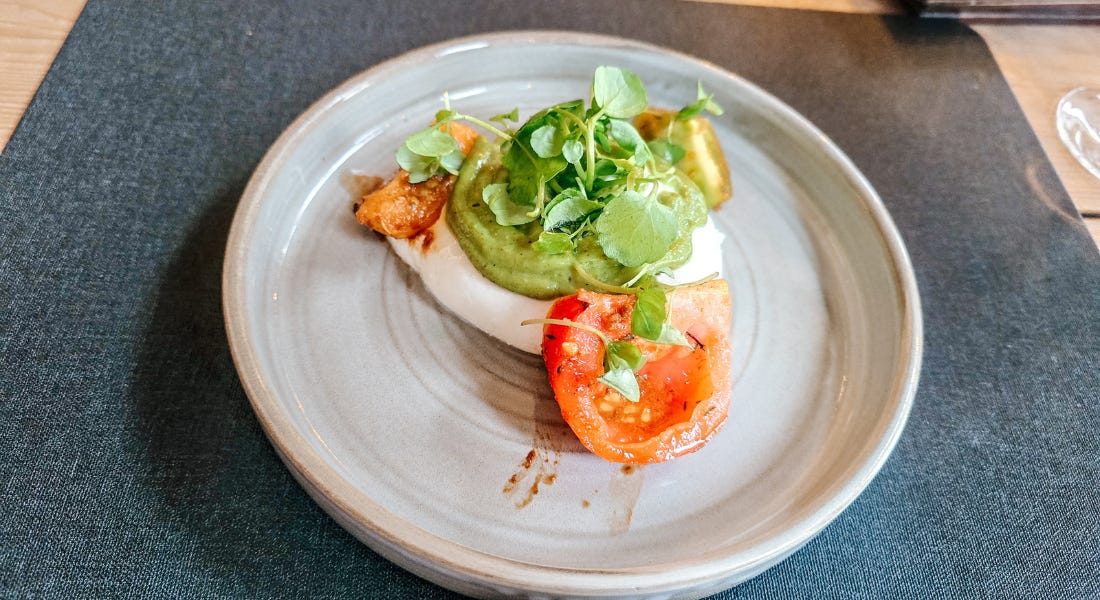 A plate of burrata and tomatoes on top of a black placemat