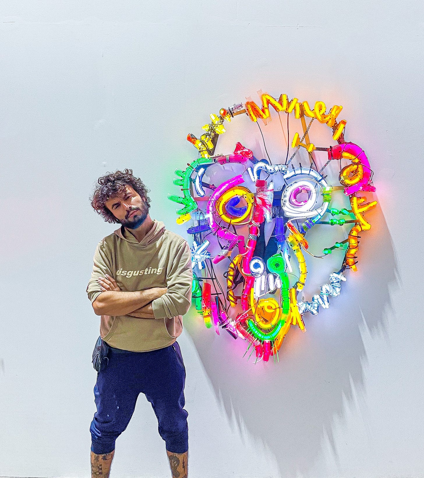 Bordalo II posing next to a neon light artwork Bordalo II posing next to a neon light artwork