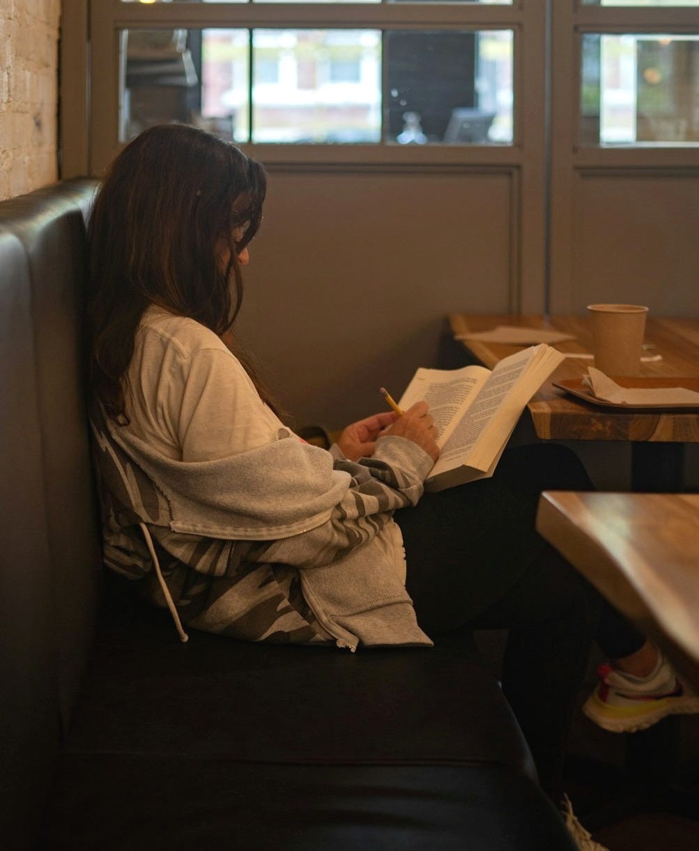 a woman sitting in a booth reading a book