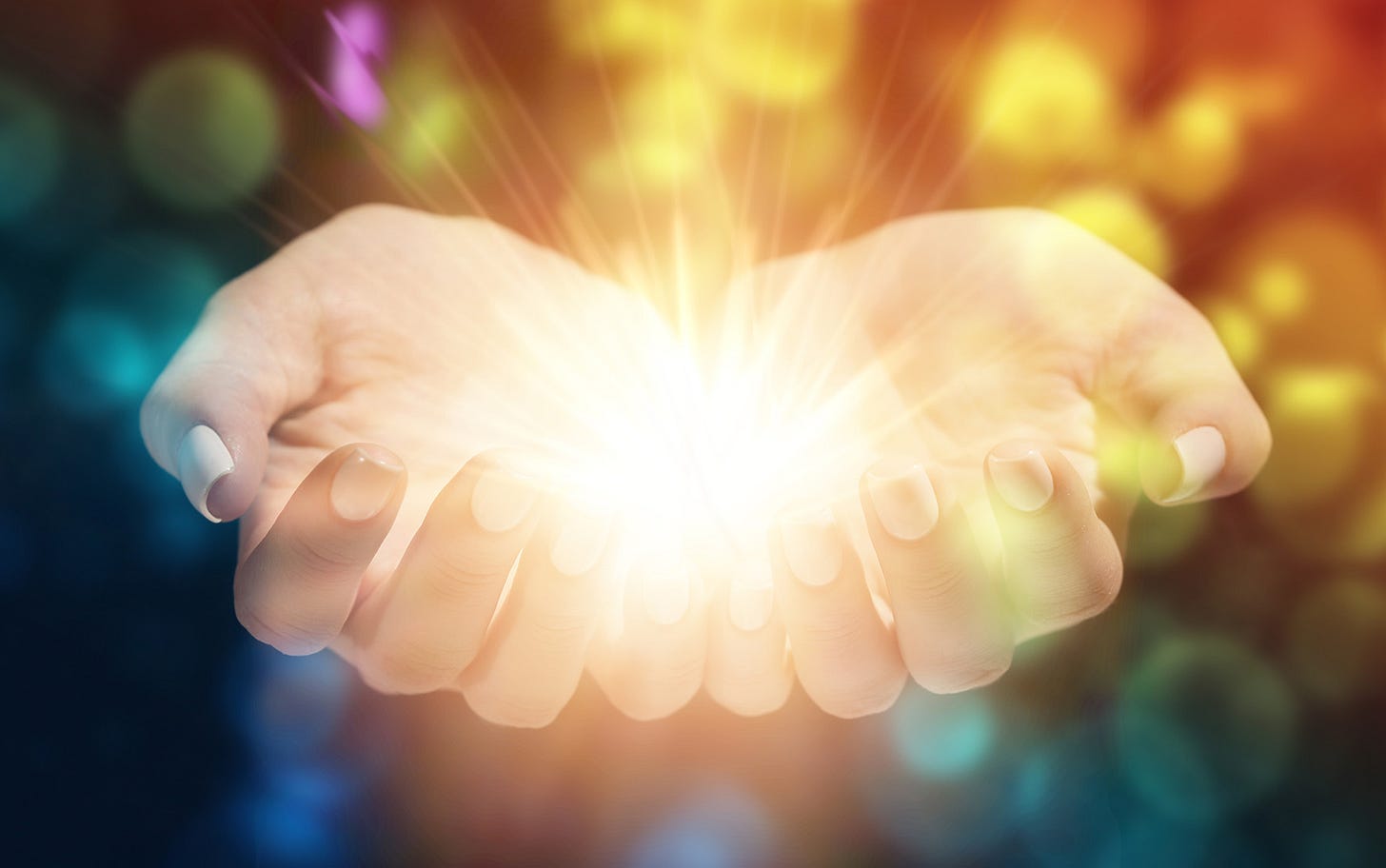 Two hands holding light with magic sparkles around