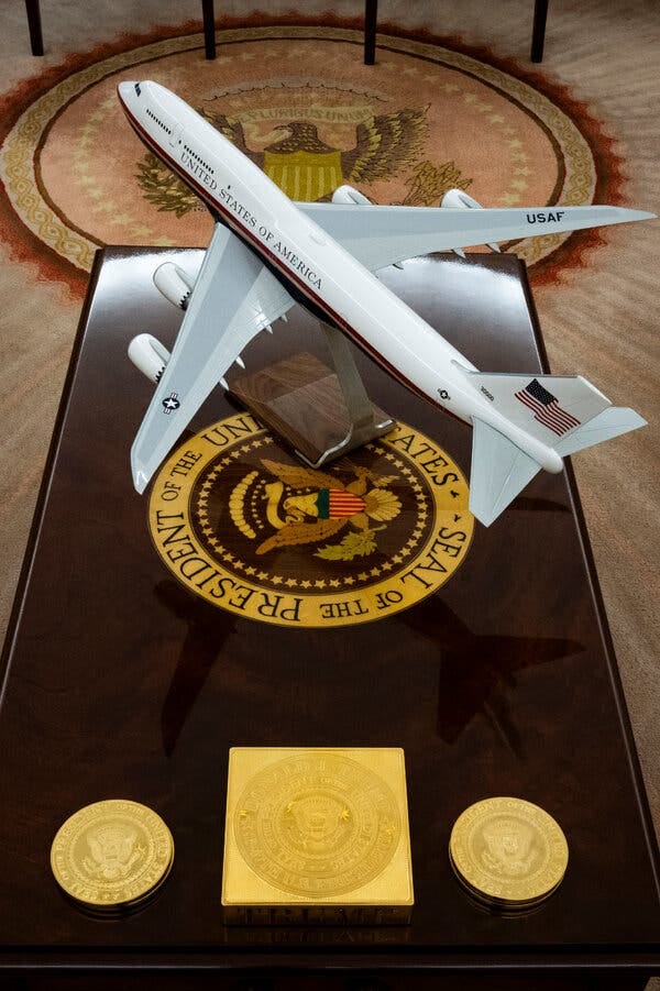 An Air Force One plane model, standing on a presidential seal on an Oval Office table.