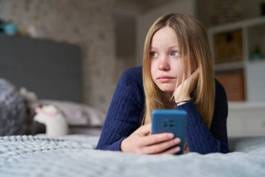Unhappy Teenage Girl With Mobile Phone Lying On Bed At Home Anxious About Social Media Online Bullying And Using Phone Too Much Unhappy Teenage Girl With Mobile Phone Lying On Bed At Home Anxious About Social Media Online Bullying And Using Phone Too Much children and phones stock pictures, royalty-free photos & images