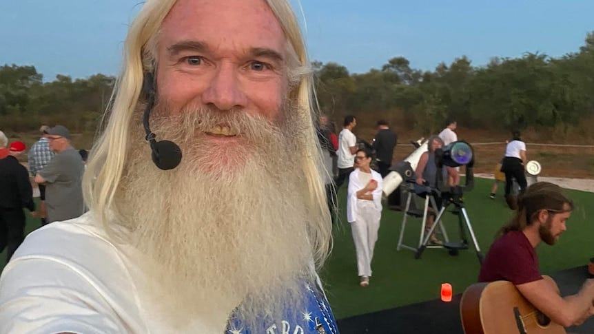 A man with a beard and headset mic smiles