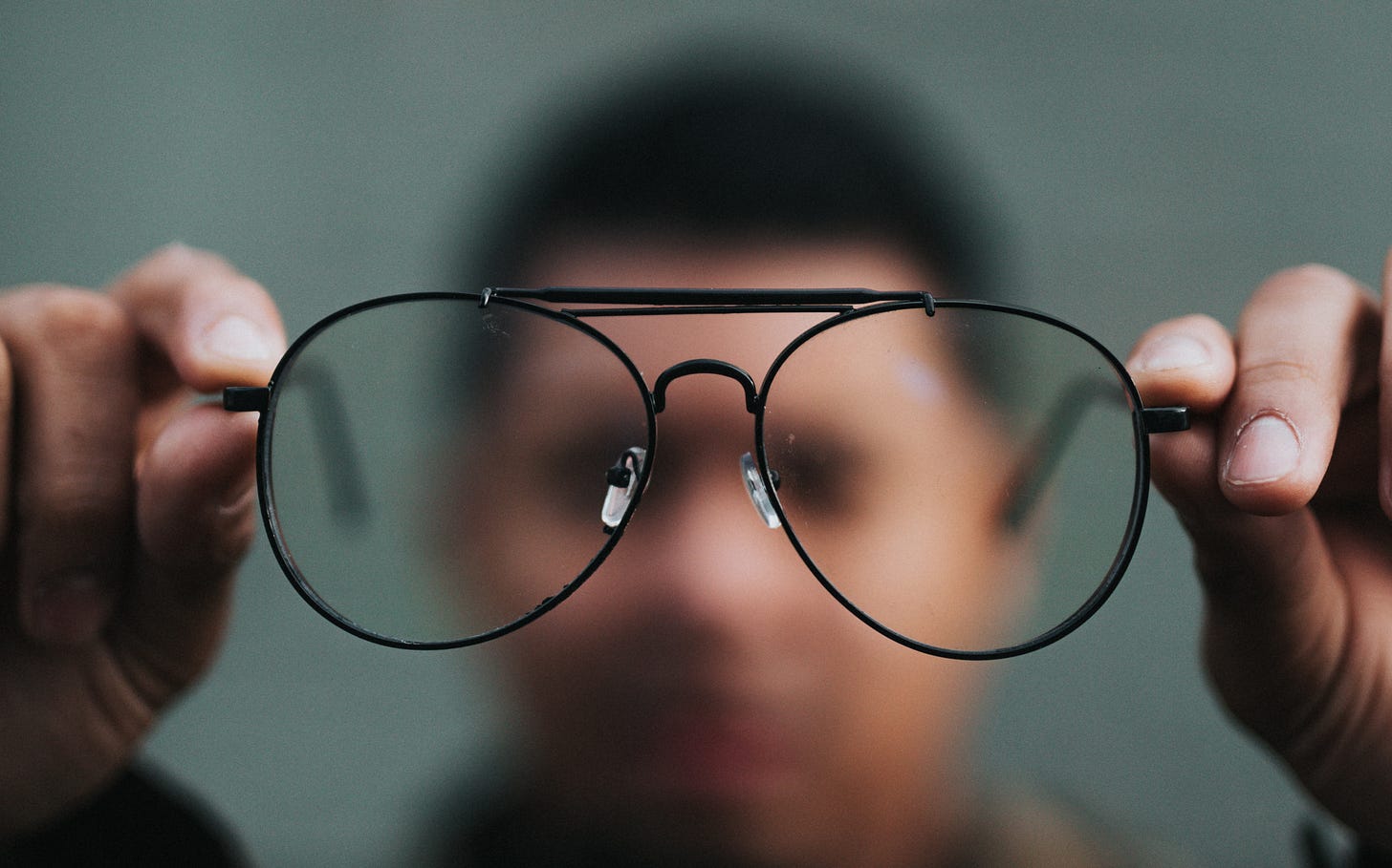 glasses in the foreground and a blurry head behind them in the background