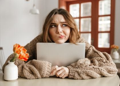 Women hugging her laptop while deep in thought. Photo courtesy of Dean Drobot via Canva.
