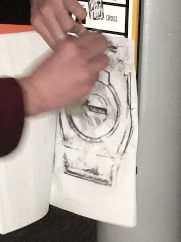 My friend, drunk, making a rubbing of a traffic light button.