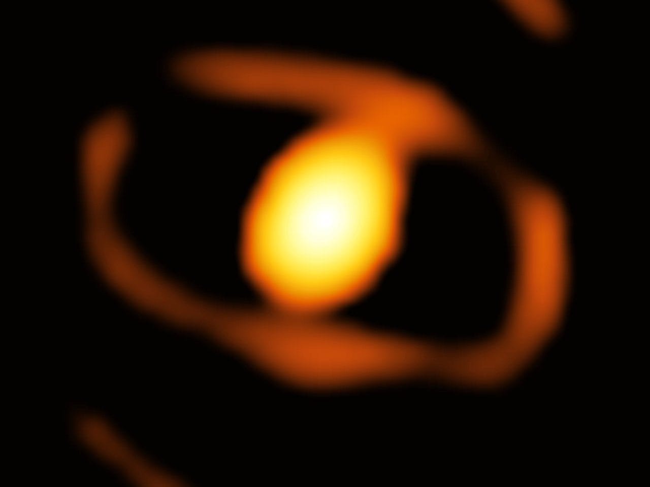 The image shows a bright oval structure, surrounded by a fainter larger ring, against a black background. The oval corresponds to the light coming from the star WOH G64 and the dust cocoon around it, while the ring may be the inner side of a torus of dust around them. The image shows a bright oval structure, surrounded by a fainter larger ring, against a black background. The oval corresponds to the light coming from the star WOH G64 and the dust cocoon around it, while the ring may be the inner side of a torus of dust around them.