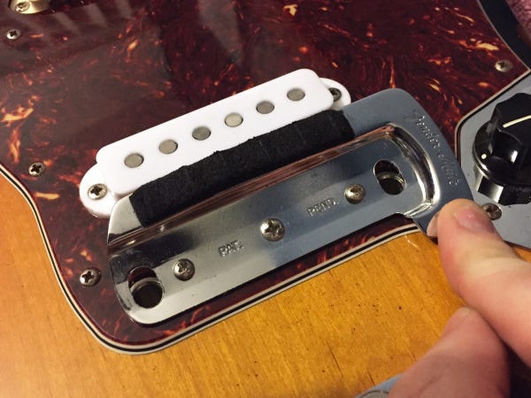 Adjusting the pickup on a guitar.
