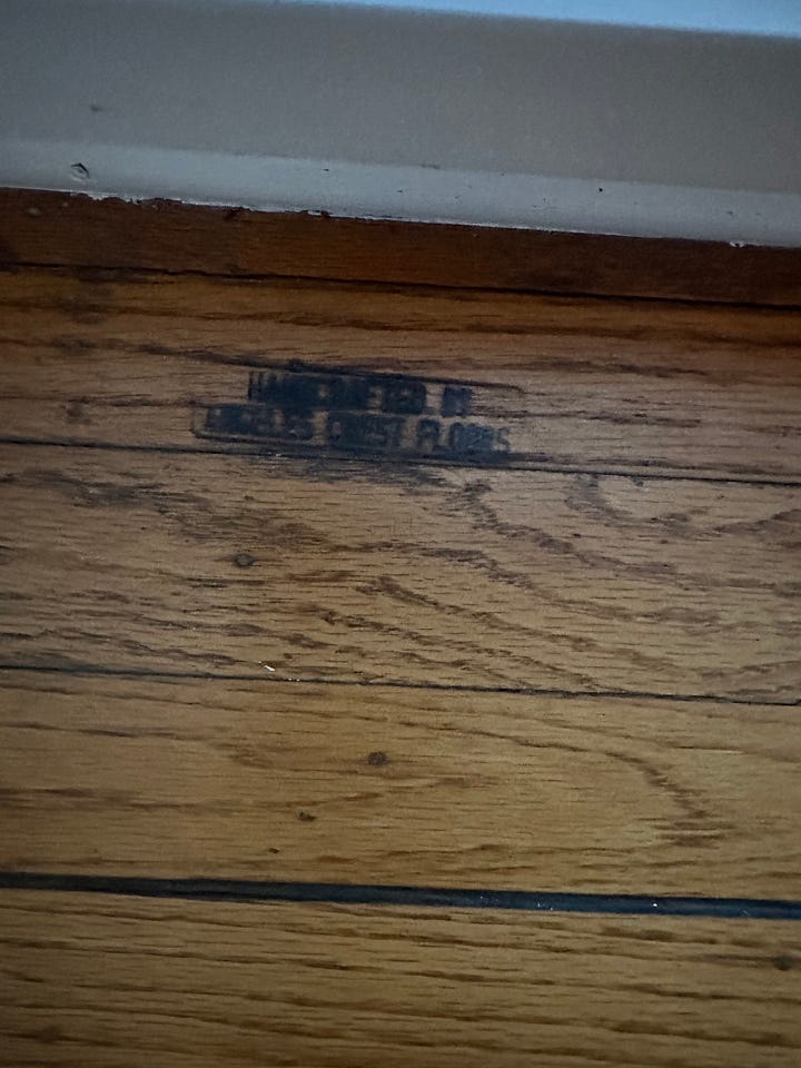 Damaged strip wood floors that are woodburned to simulate wide plank flooring with faux round peg fasteners. Also with the company's name branded into the corner.